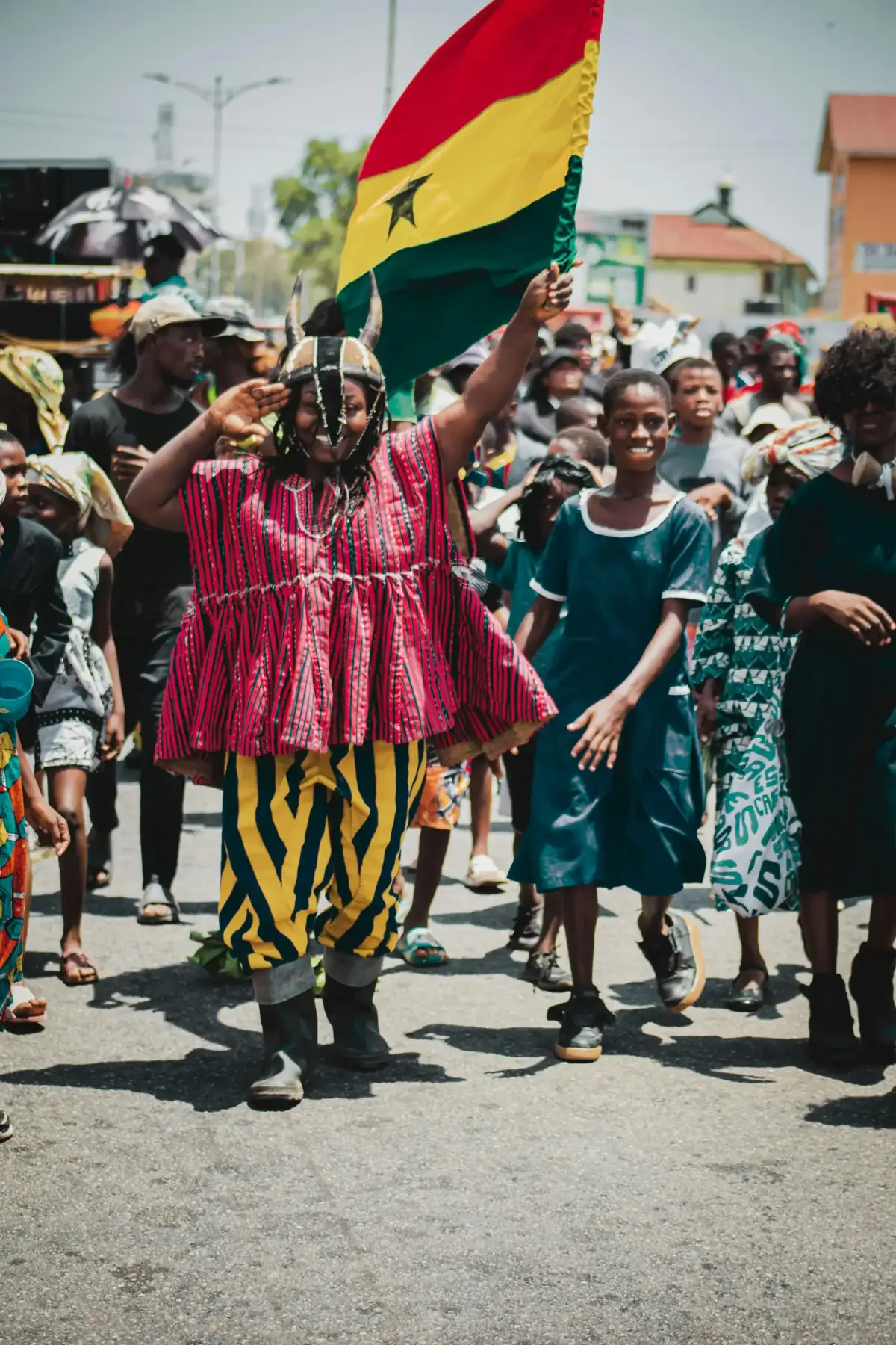 Two women wrapped in the Ghanaian flag, laughing on a beach